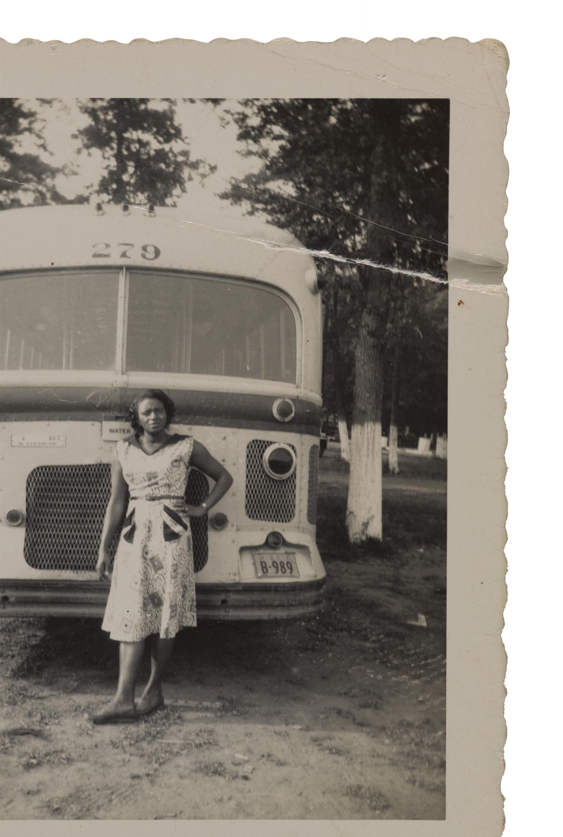 Black and white snapshot of a woman standing in front of a bus