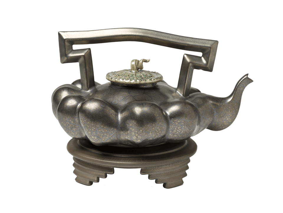 Squash-shaped teapot in profile. Curling finial, rectangular handle, and stacked rectangular feet. Covered in a dark grey metallic glaze.