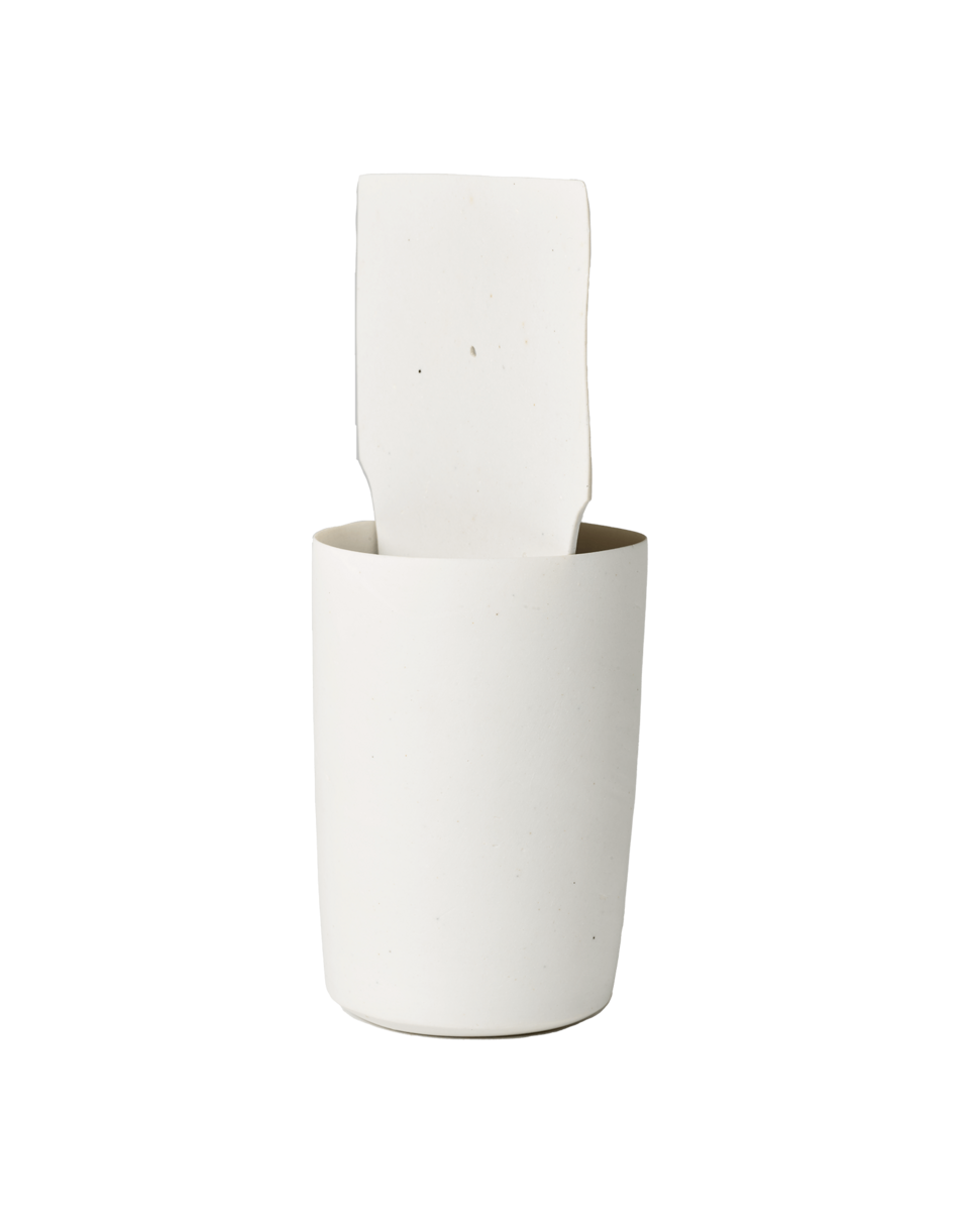 Tall, round, white cup with a white, square-shaped slice of clay on the interior of the cup.