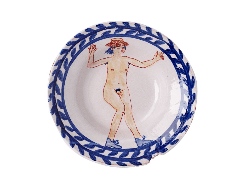Ceramic plate with a decorative floral border and an illustration of a dancing nude man wearing a full-brimmed hat and shoes