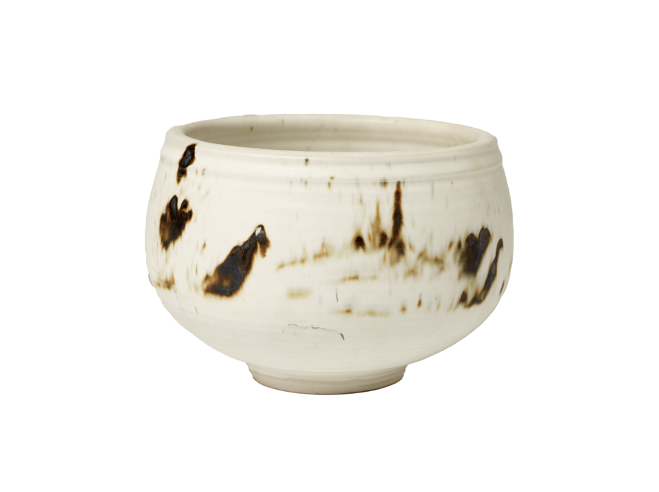 White bowl on a small circular foot with irregular brown marks. 