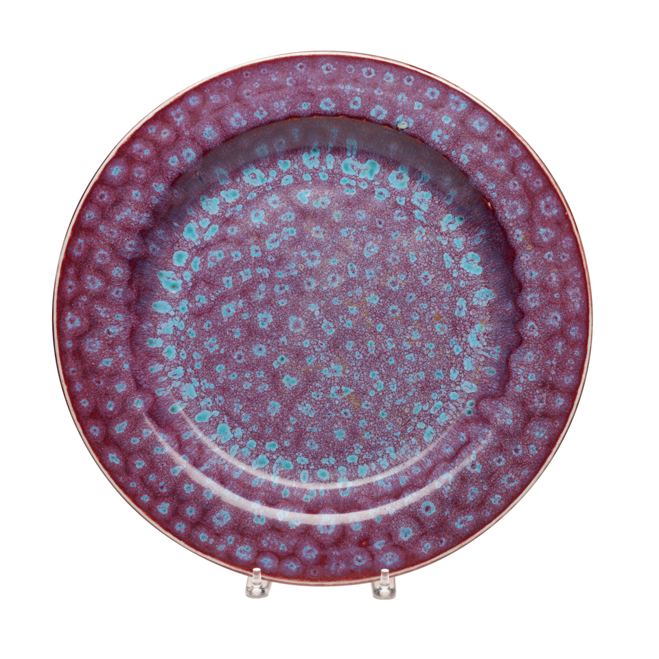 Circular plate with dark purple glaze and spots of light blue glaze in concentric circles.