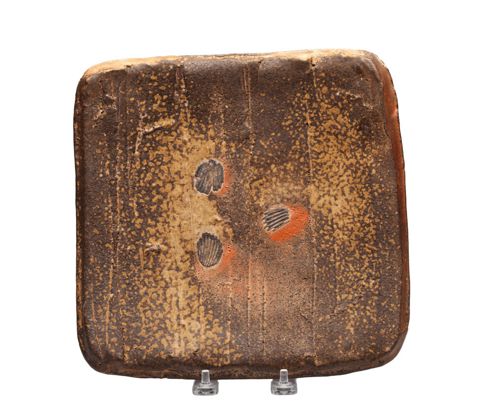 Brown square plate with tan splatters. In the center, three indentations in the shape of shellsare surrounded by red marks