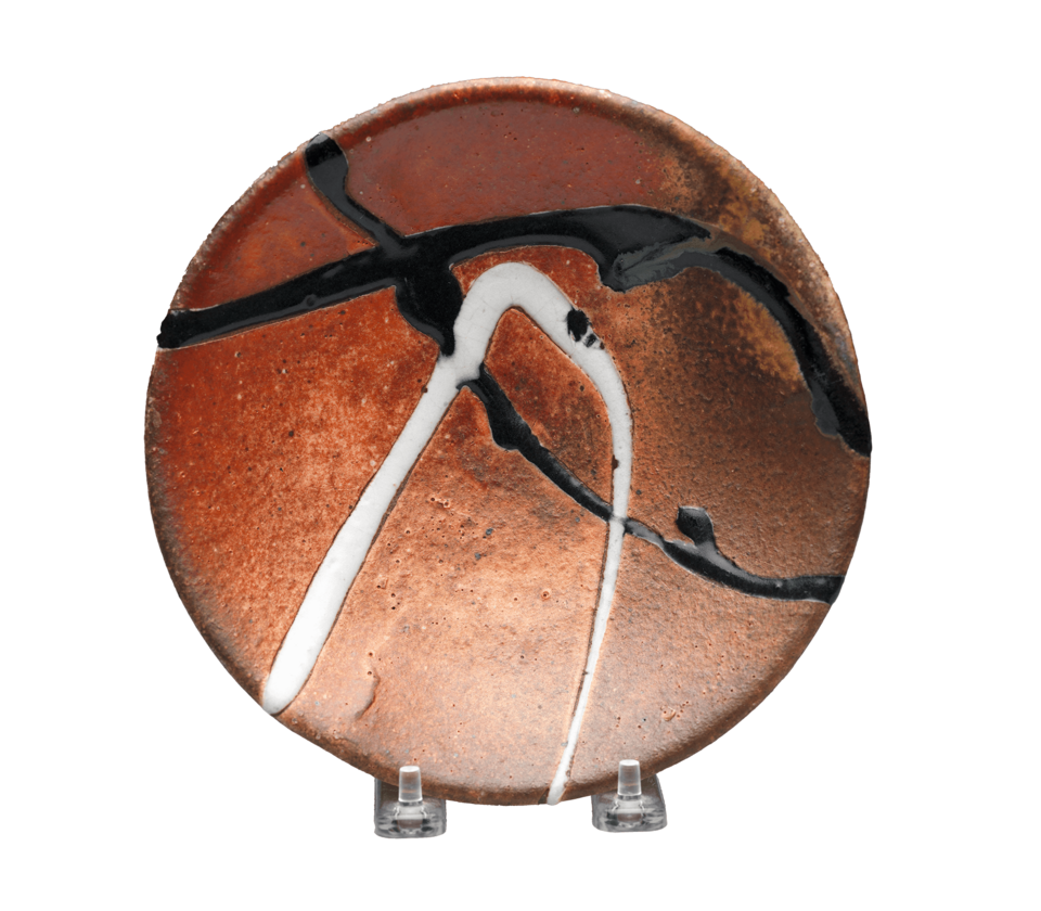 A rust-colored circular plate with splashes of white and black.