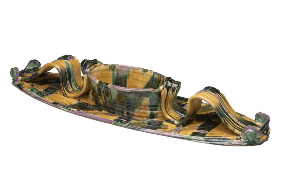 A long oval platter with attached oval bowl in the center. Long curving handles on either side of the bowl. Covered in mottled shades of yellow, green, and black