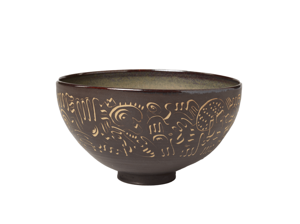 Dark brown bowl on a small, circular foot. Tan colored decorations scratched into clay covering the exterior. 
