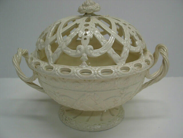A creamware chestnut basket with sculptural woven handles, sculpted foot, and the lid has decorative cutouts. 