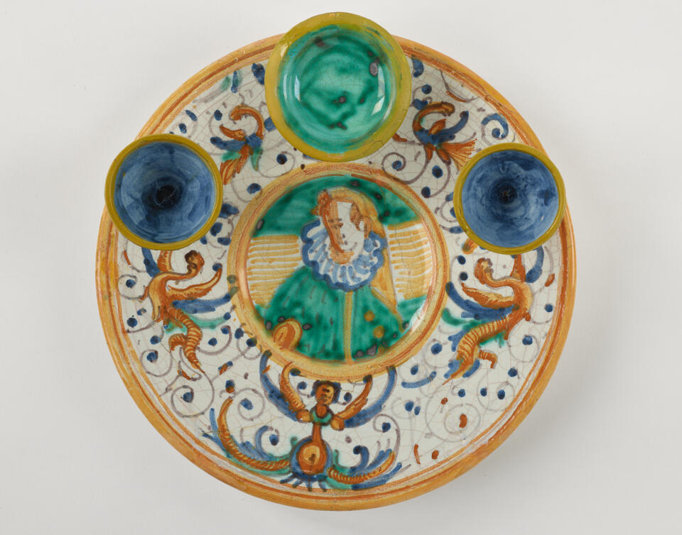  A lead-glazed earthenware plate that has different compartments. There are yellow, white, blue, and green glazed decorations.