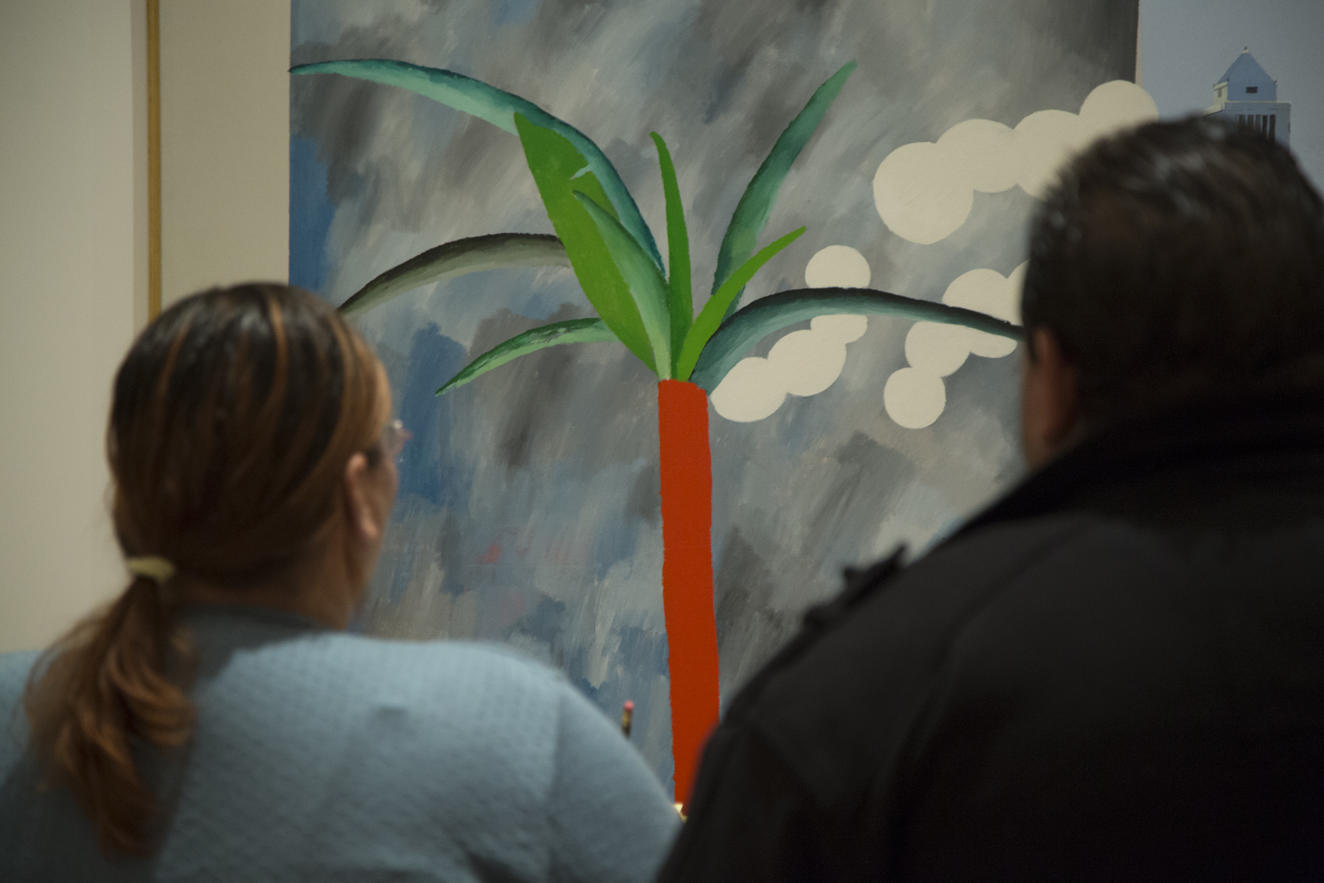 Two people looking at a painting of a palm tree