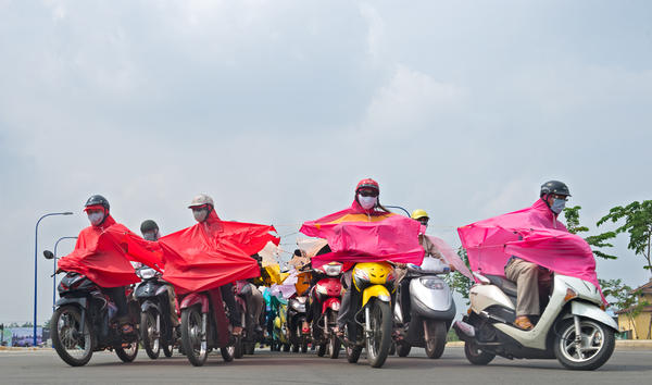 people on scooters wearing pink and red ponchos
