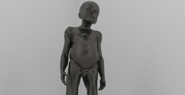 A photograph of a sculpture of a naked, dark-skinned, child with a distended belly, swollen arms, and a bald head. The photograph is angled up showing the child from the knees up.  