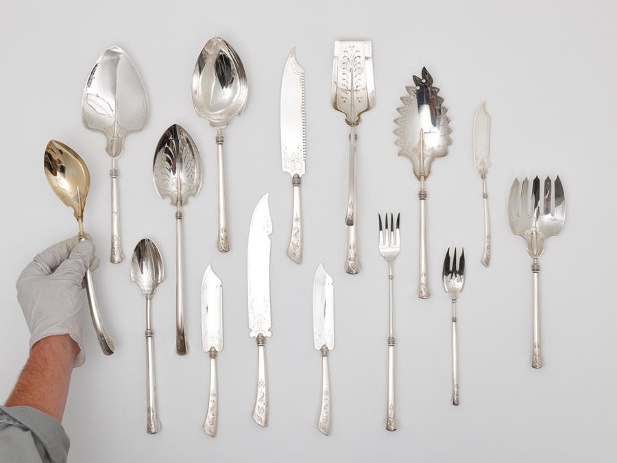 group of flatware with hand placing serving spoon into frame